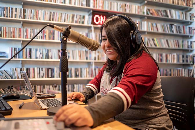 Student operating KZUU college radio in front of a mic.