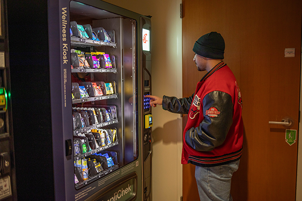 student pushes button on wellness kiosk