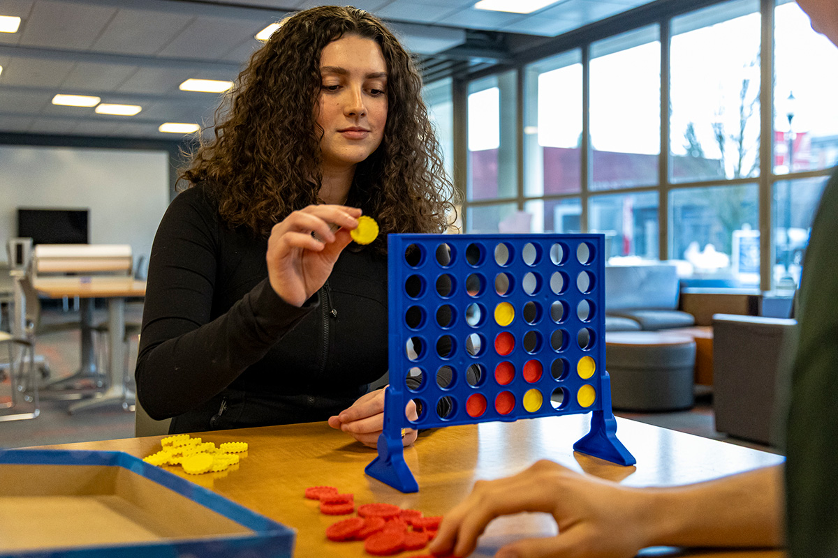 student gets ready to place yellow disc in connect 4 